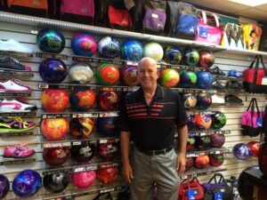 Smiling man standing in front of wall of bowling balls